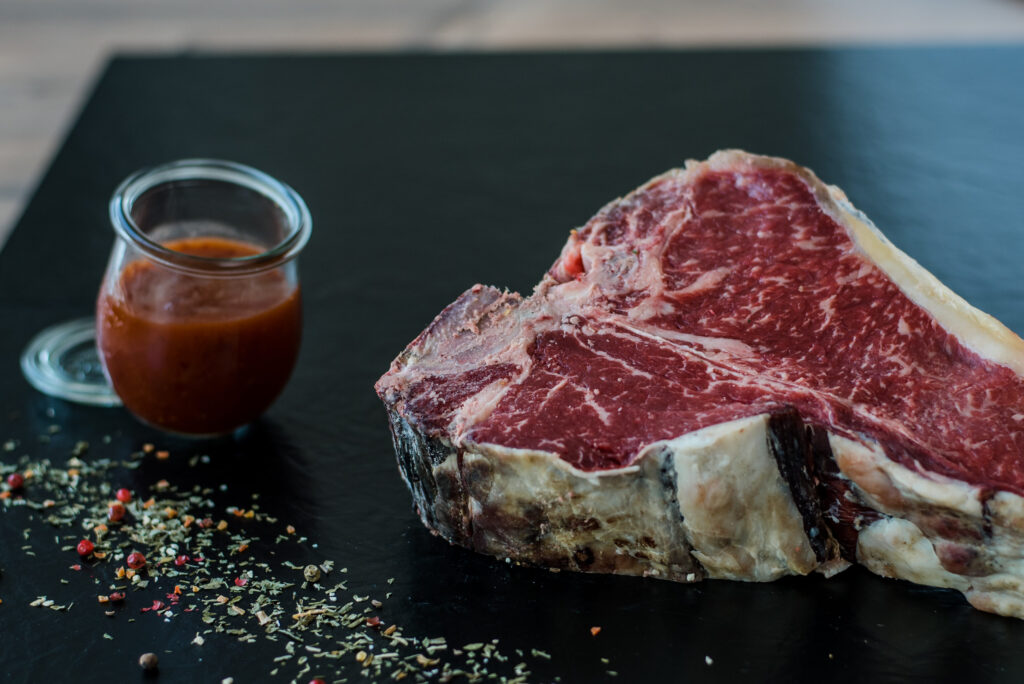 Bild von Steak auf Brettchen mit Soße dazu.